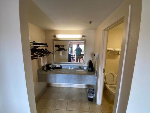 a bathroom with a sink and a person in the mirror at Motel 6 Oklahoma City OK Fairgrounds West in Oklahoma City