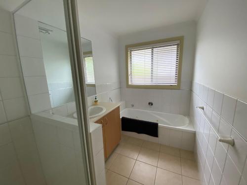 a white bathroom with a tub and a sink at Perfect Location in Inverloch