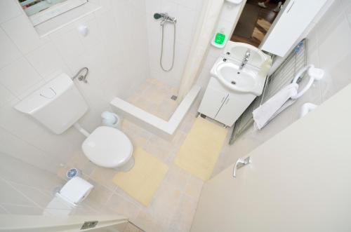a white bathroom with a toilet and a sink at Apartment Croatia Art in Drasnice