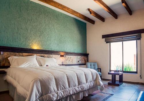 um quarto com uma cama grande e uma parede verde em Miia Hotel Boutique em Bernal