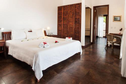 a bedroom with a large white bed with flowers on it at Villas de Jardin self-catering in Port Glaud