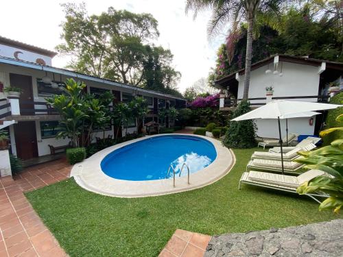 a swimming pool with an umbrella and chairs and a building at Casa Dalinda in Valle de Bravo