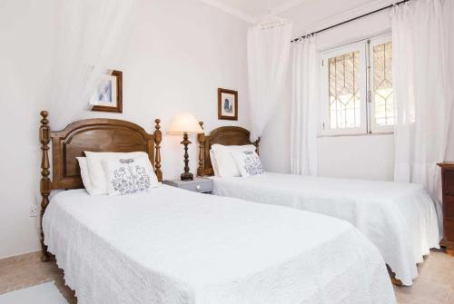 BordeiraにあるJacarandaの白い壁のベッドルーム(ベッド2台、窓付)