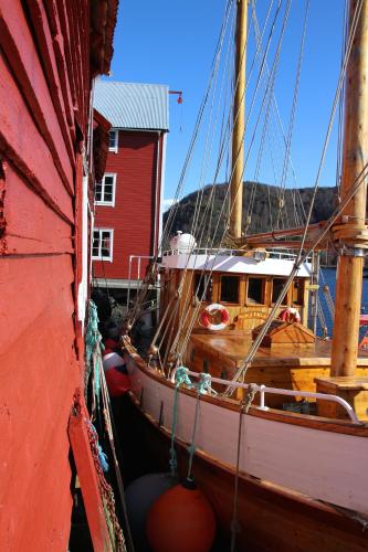 a boat docked next to a red building at Skomakergarden in Ulsteinvik