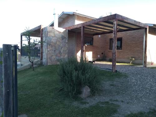 una casa de ladrillo con un pabellón de madera en un patio en Cabañas Quimera en Santa Rosa de Calamuchita