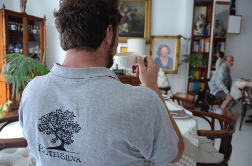 a man drinking a cup of coffee in a room at Hotel Silva in Alberobello