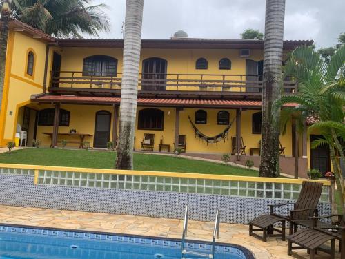a yellow house with a swimming pool in front of it at Casa em Ilhabela - Próxima à Praia do Curral in Ilhabela