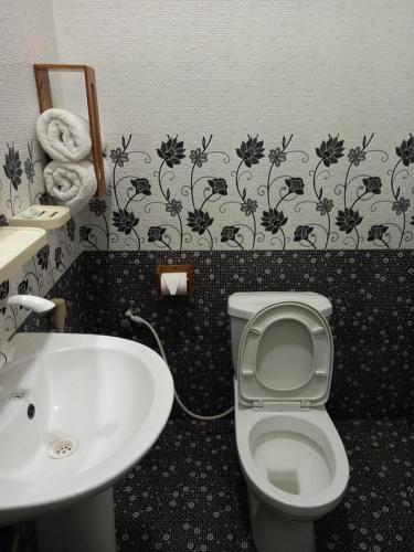 a bathroom with a white toilet and a sink at Villa Luxez in Kalmunaikudiyiruppu