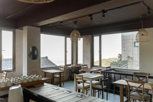 ein Restaurant mit Tischen und Stühlen und großen Fenstern in der Unterkunft Mountain Traveler Inn in Jiufen