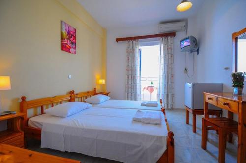 a bedroom with two beds and a television in it at Hotel Prassino Nissi in Moraitika