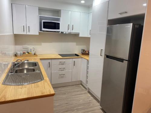 a kitchen with white cabinets and a stainless steel refrigerator at New England Motor Lodge in Glen Innes