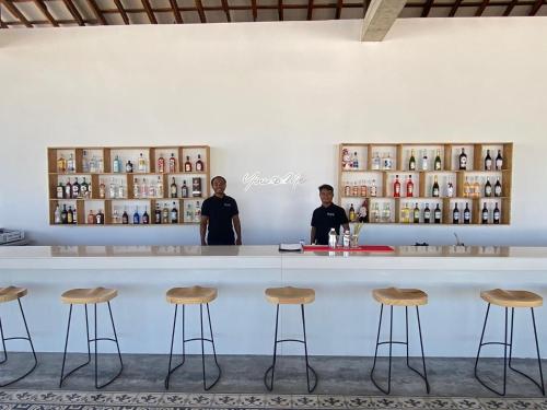 two men standing behind a bar with stools at You&Me Resort in Koh Rong Island