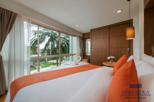 a bedroom with a large bed with a large window at Simantra Private Villas in Cha Am