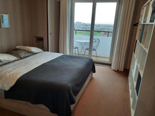 een slaapkamer met een bed en een balkon met een tafel bij L Ô in Oostende