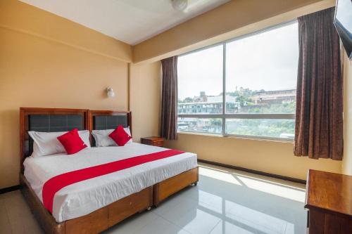 Un dormitorio con una cama con almohadas rojas y una gran ventana. en OYO Hotel Totonacapan, Papantla, en Papantla de Olarte