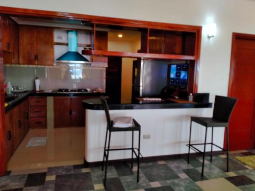 a kitchen with two bar stools and a stove at Cesar Villa sea side in Tagudin