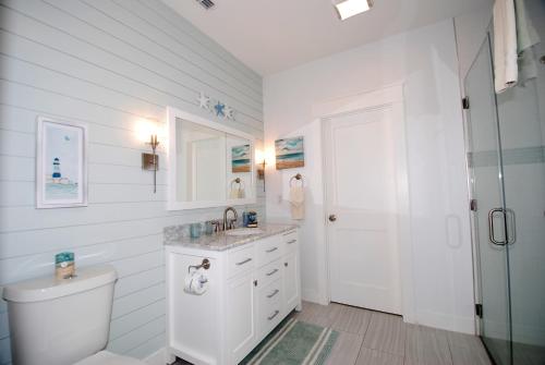 Baño blanco con aseo y lavamanos en Anchors Aweigh cottage, en South Padre Island