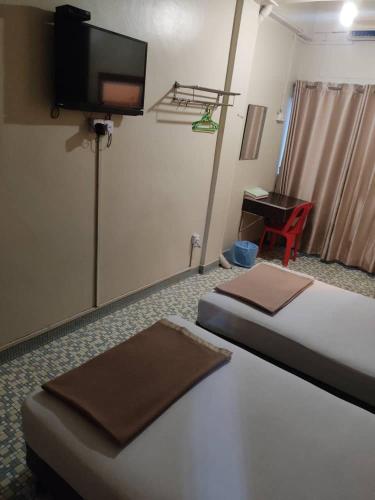 a hotel room with two beds and a flat screen tv at Marina Hotel Kemaman in Kemaman