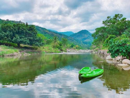 een paar groene boten op een rivier bij คูร์โดวเเอนด์เเซนด์วิลล่า in Kiriwong