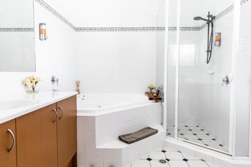 baño blanco con ducha y lavamanos en The Bearded Dragon Boutique Hotel, en Mount Tamborine