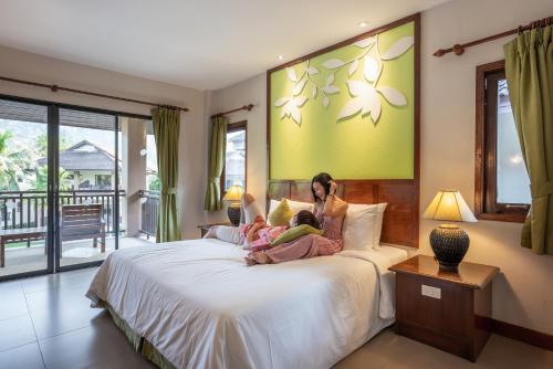 a woman and a child laying on a bed at The Leaf Oceanside by Katathani - SHA Extra Plus in Khao Lak
