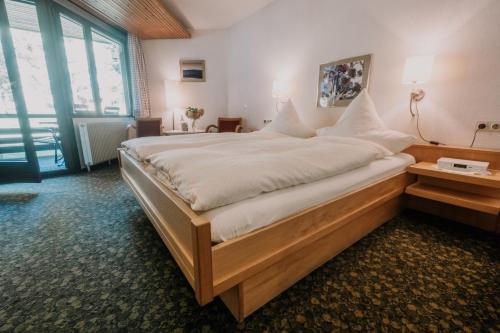a large bed in a room with a large window at Akzent Hotel Lawine in Todtnau