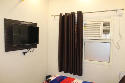 a living room with a television and a window at Hotel Gopal in Haridwār