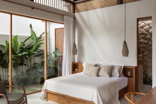 een slaapkamer met een bed en een groot raam bij Las Lunas Villas Canggu in Canggu