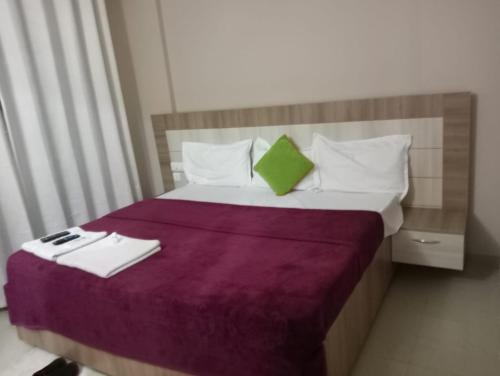 a bed with a purple blanket and a green pillow at Omaxe Krishna Aavas in Vrindāvan