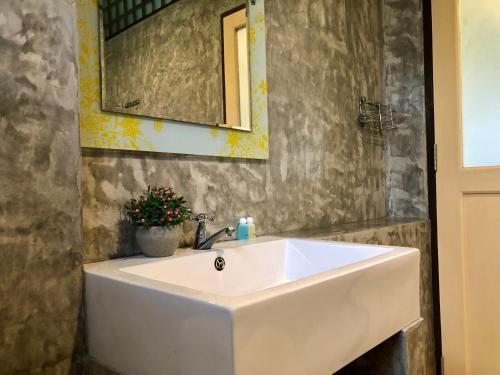 La salle de bains est pourvue d'un lavabo blanc et d'un miroir. dans l'établissement Pop riverside trat, à Trat