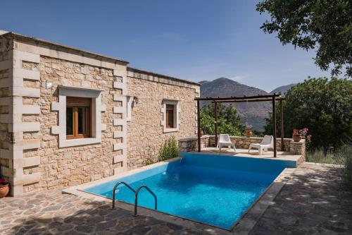 a pool in front of a stone house with two chairs at Koules Estate, with Private Pools & BBQ - embracing Nature, By ThinkVilla in Argoulión