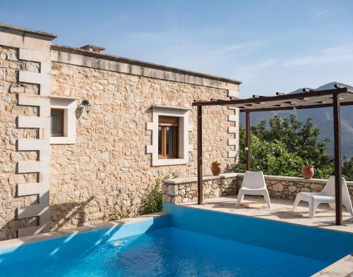 a house with a swimming pool and two chairs at Koules Estate, with Private Pools & BBQ - embracing Nature, By ThinkVilla in Argoulión