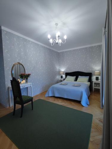 een slaapkamer met een bed, een stoel en een kroonluchter bij Villa Art deco in Dębica