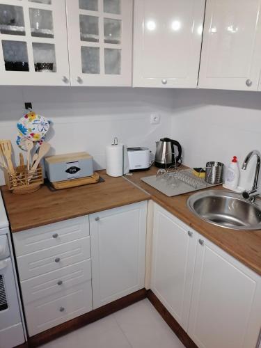 a kitchen with white cabinets and a sink at Apartman Štimac in Petrovaradin