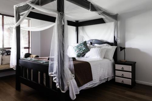 ein Schlafzimmer mit einem Himmelbett und weißen Kissen in der Unterkunft The Bearded Dragon Boutique Hotel in Mount Tamborine
