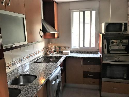 a kitchen with a sink and a stove top oven at Apartamento junto al río en entrada ruta Cahorros in Monachil