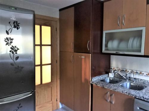 cocina con nevera de acero inoxidable y fregadero en Apartamento junto al río en entrada ruta Cahorros, en Monachil