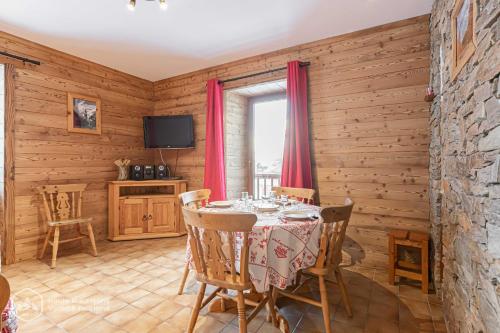 a dining room with a table and a tv at 153 Rue des Rochers in Lanslevillard