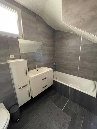 a bathroom with a sink and a tub and a toilet at Appartement Bes,, Chaleureux et confortable avec entrée indépendante in Wittenheim