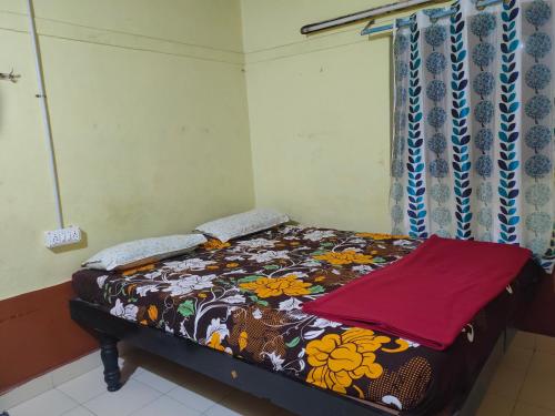 um pequeno quarto com uma cama com um cobertor floral em Sudhaahomestay em Hampi