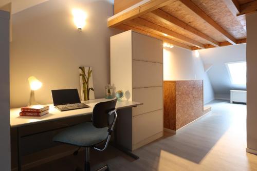 a desk with a laptop and a chair in a room at Le cosy 40 - maison typique au centre de Malmedy in Malmedy