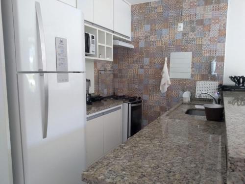 a kitchen with a white refrigerator and a sink at Imbassaí Bahia Temporada Térreo in Imbassai