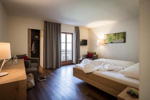 Habitación de hotel con cama y sala de estar. en Hotel Weingut Stroblhof, en Appiano sulla Strada del Vino