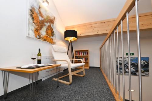 an office with a desk and a chair and a bottle of wine at Salzgeber Appartements in Sankt Gallenkirch