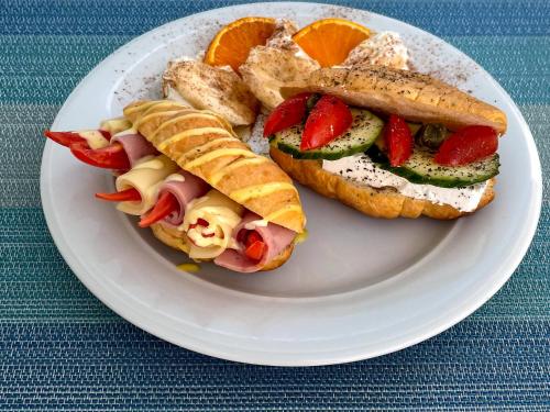 a white plate with a sandwich with fruit and vegetables at Stratos Hotel in Pythagoreio