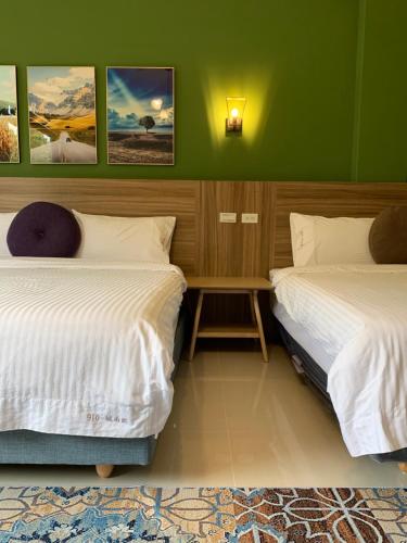 two beds in a room with green walls at 910 Hostel 城南館-自助入住 in Yuli