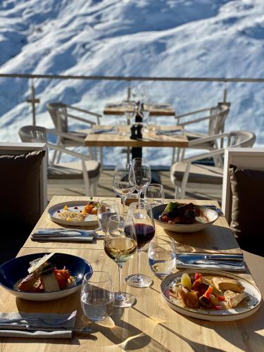 a table with plates of food and glasses of wine at Ours Blanc Hotel & Spa in Les Menuires