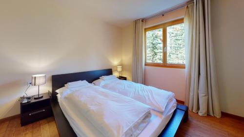 a large bed in a bedroom with a window at Chesa Seraina Abitaziun Seraina 4 - Sand - Madulain in Madulain