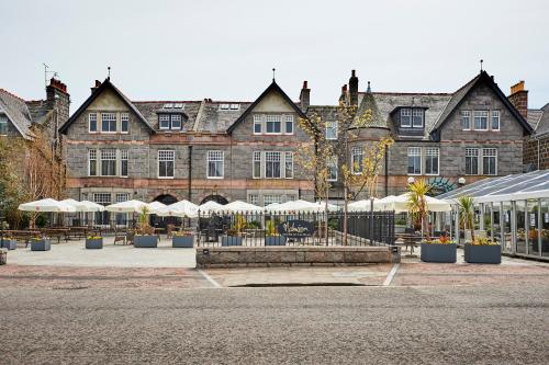 a large building with tables and umbrellas in front of it at Malmaison Aberdeen in Aberdeen