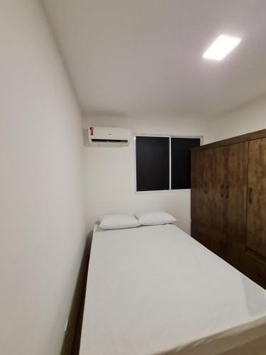 - une chambre avec un lit blanc et une armoire en bois dans l'établissement Ao lado do shopping com piscina e ar condicionado., à Caruaru